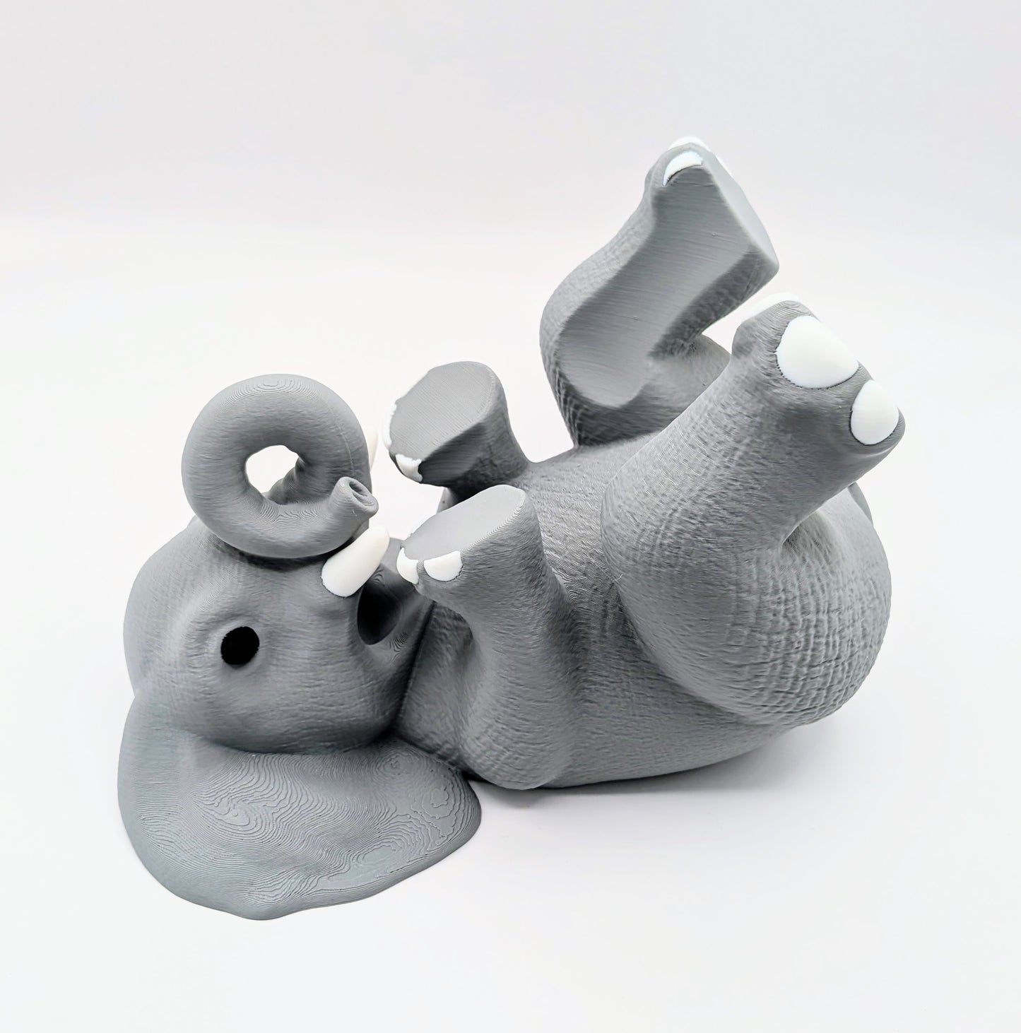 Charming gray elephant wine holder in a playful, reclining position, perfect for home decor and unique conversation piece.