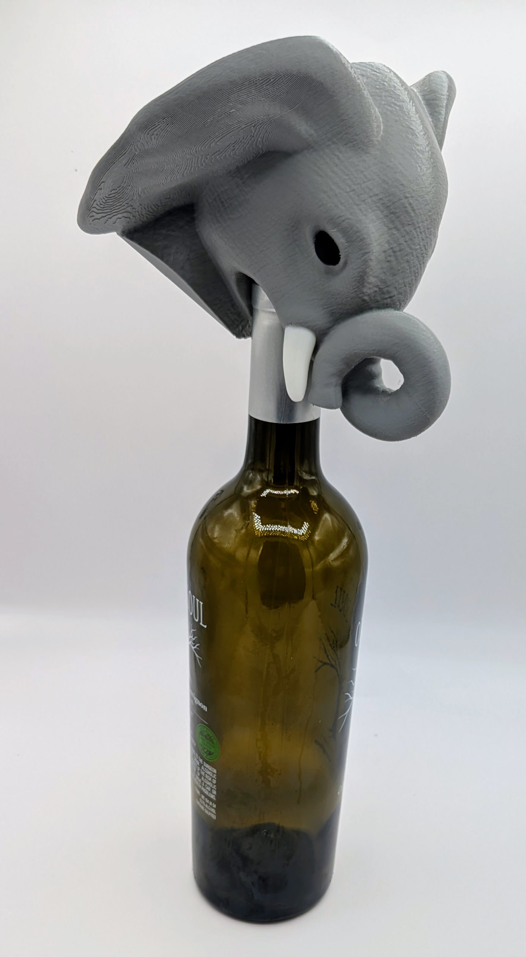 Elephant wine stopper on a green bottle, showcasing a playful gray elephant design for unique home decor.